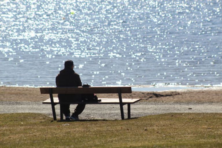 Person sitting in solitude on a bench by the sea