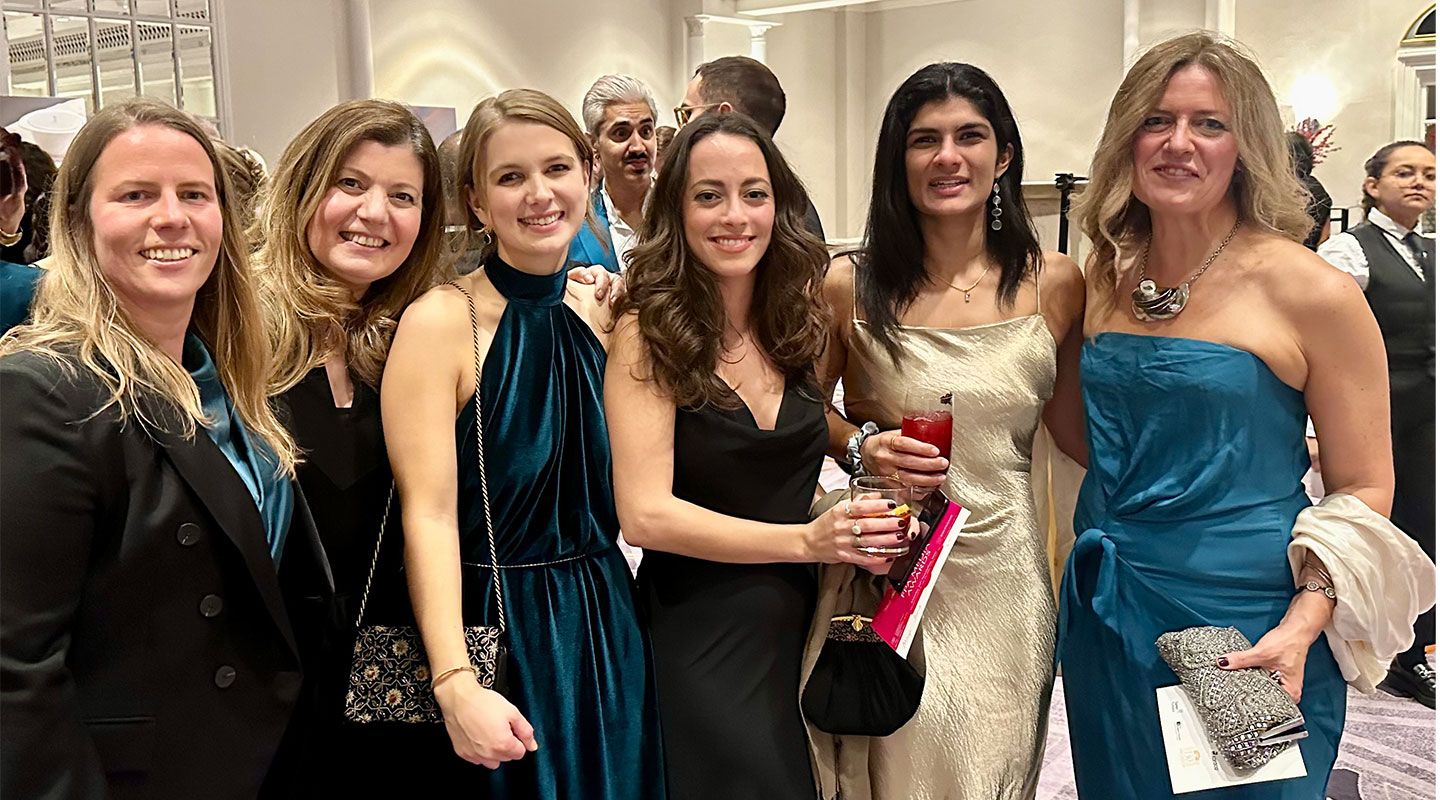 Winner and recent alumna Maya Saad stands in the middle holding her award. She is surrounded by fellow student nominees and City journalism academics. They are all wearing formal dresses.