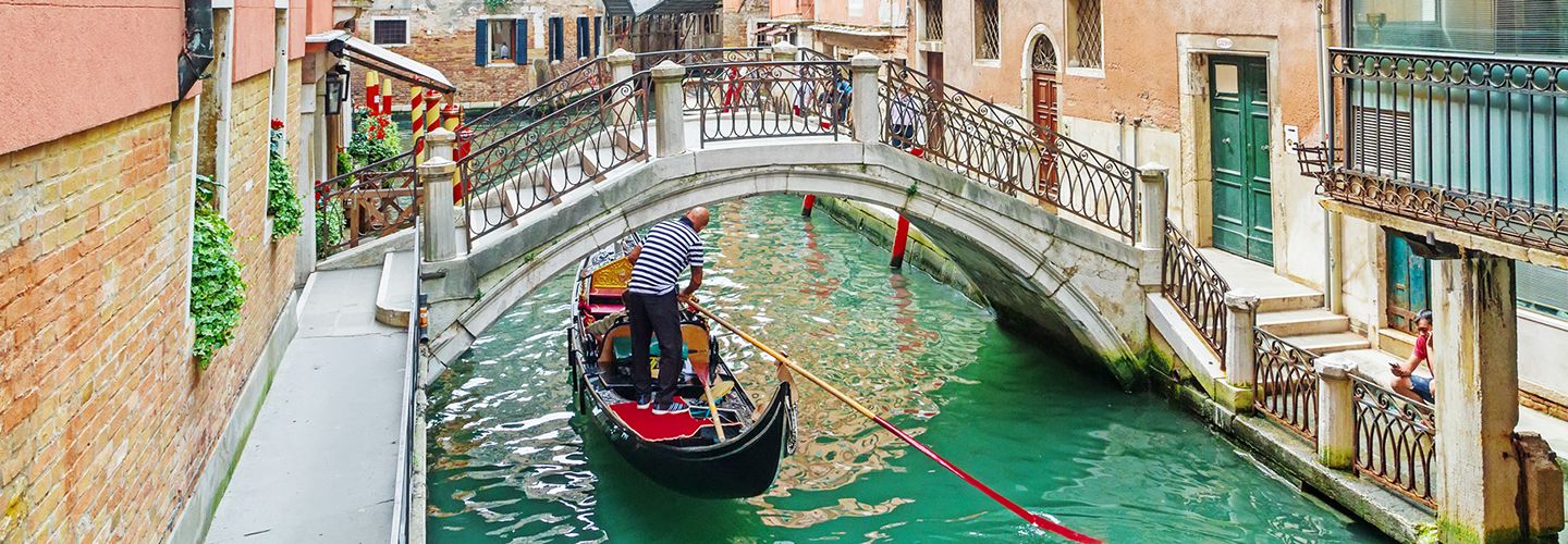 Gondola boat going under a bridge in Venice, Italy