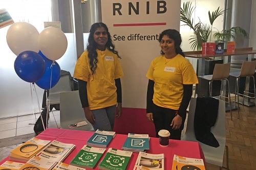 Two City Optometry students attending to the RNIB stand at the low vision day event at St Thomas' Hospital
