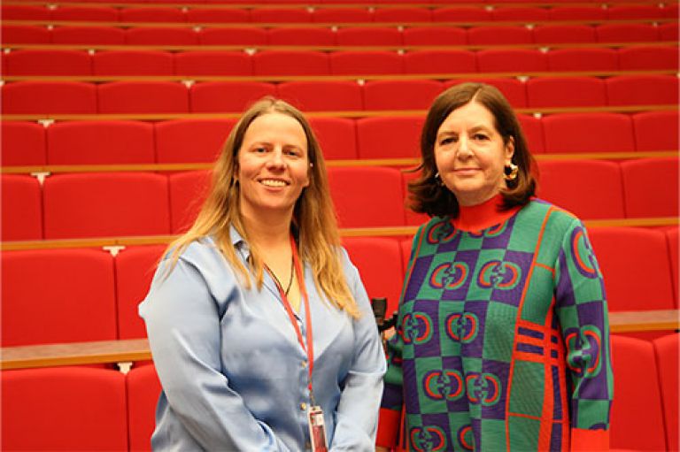 Prof Mel Bunce and journalist Dorothy Byrne stand in front of rows of red seats and smile to the camera