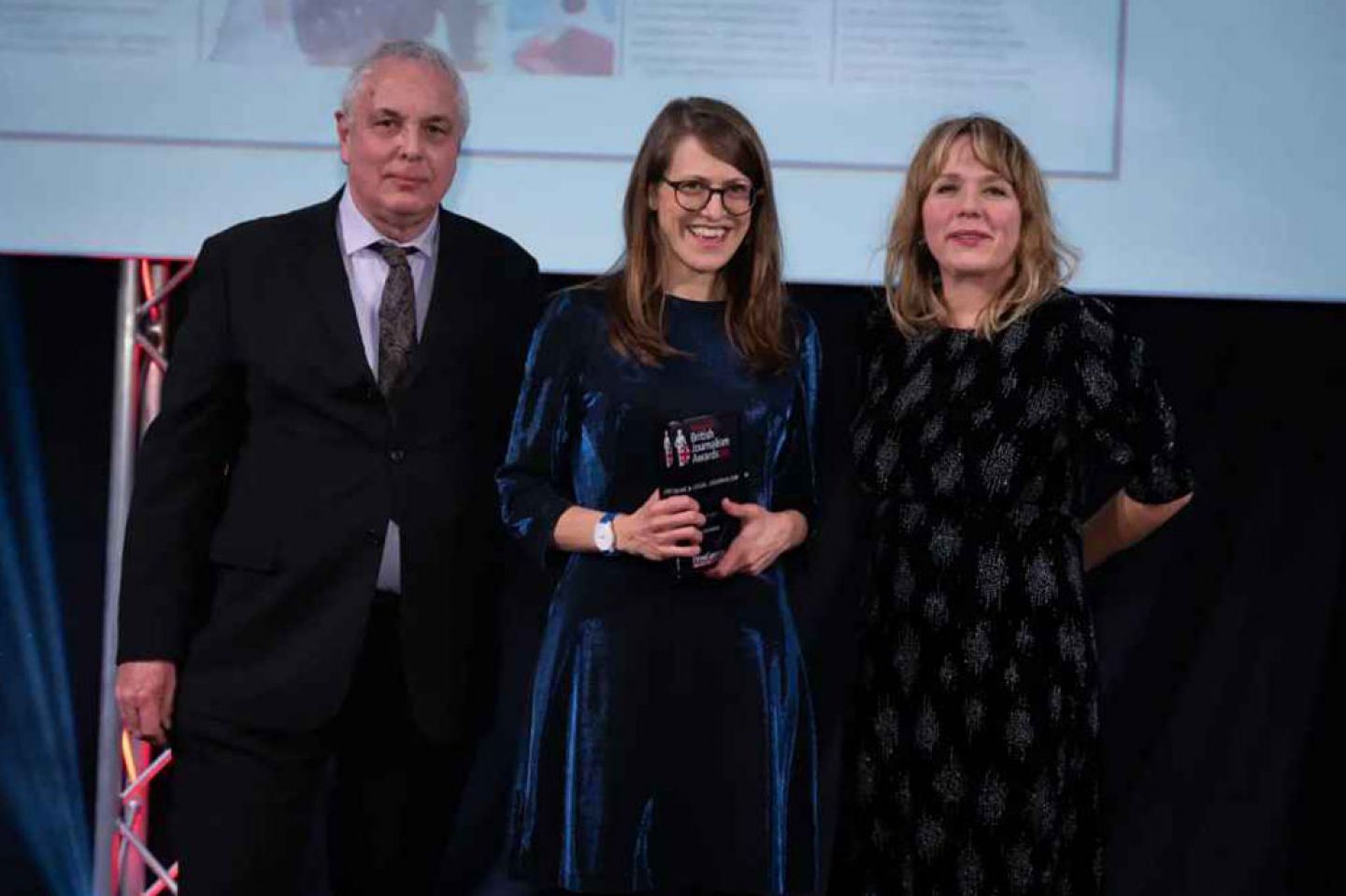 Alumna Emily Dugan stands in the middle of the picture holding her award at the British Journalism Awards 2023.