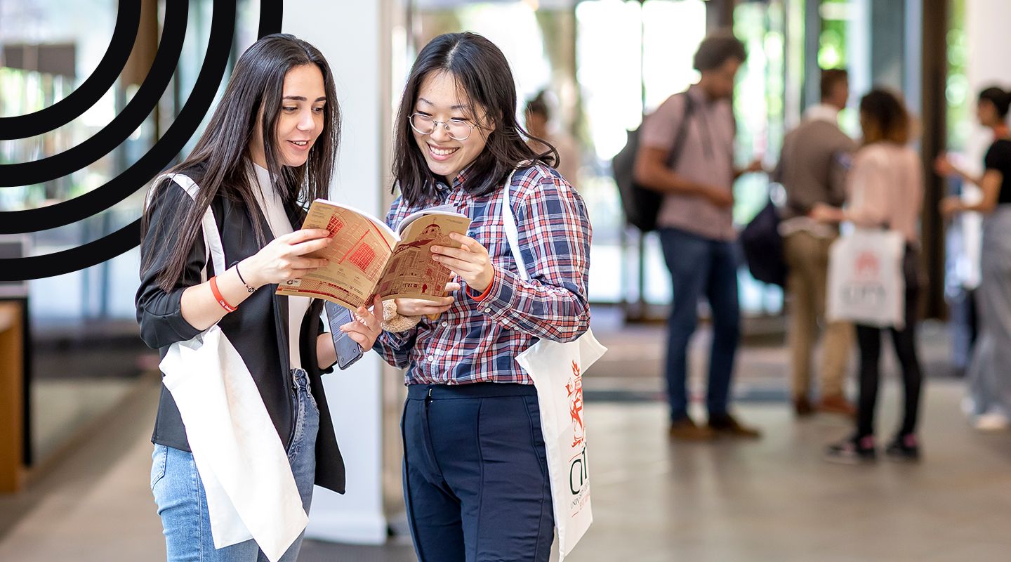 Two female students looking at a City prospectus