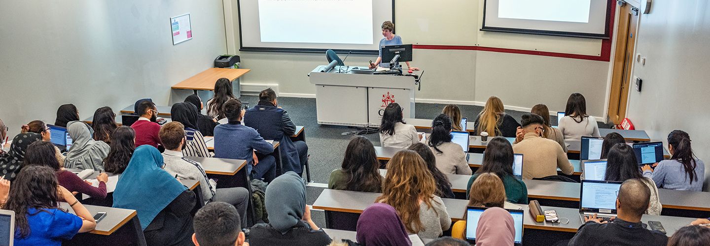 Female academic presenting to a lecture hall full of student