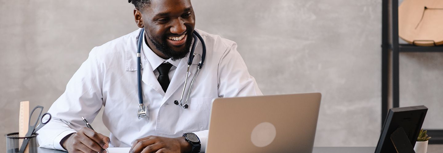 Smiling young black doctor on a video call using his laptop. 