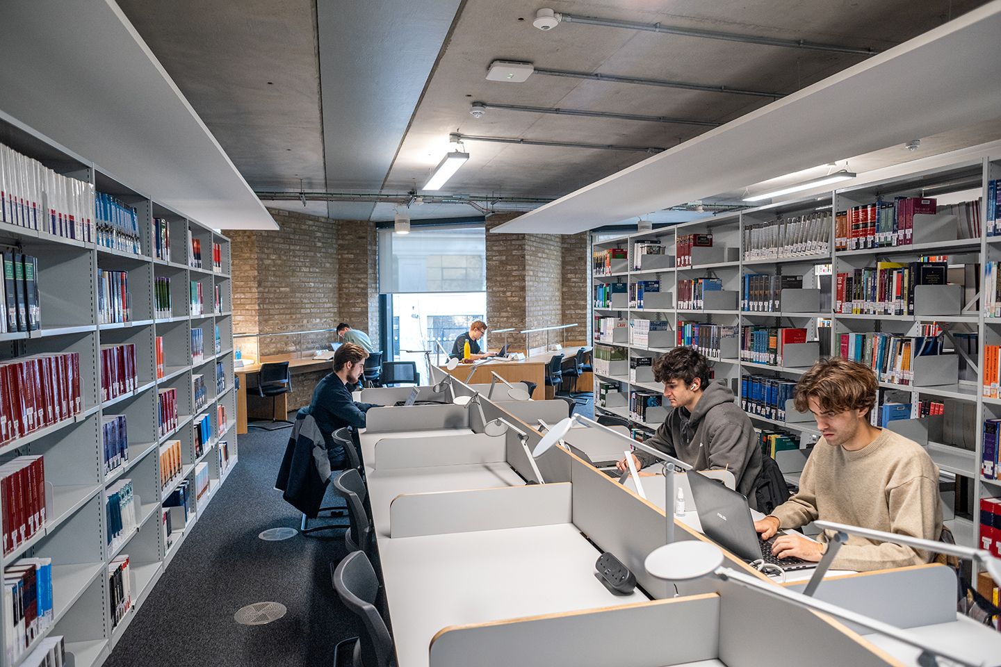 Law students on their laptops sat at individual study desks in a light and airy law library