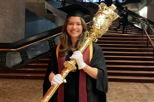Student Union President Gesmina Tsourrai carries the ceremonial mace at the winter graduation ceremonies at the Barbican