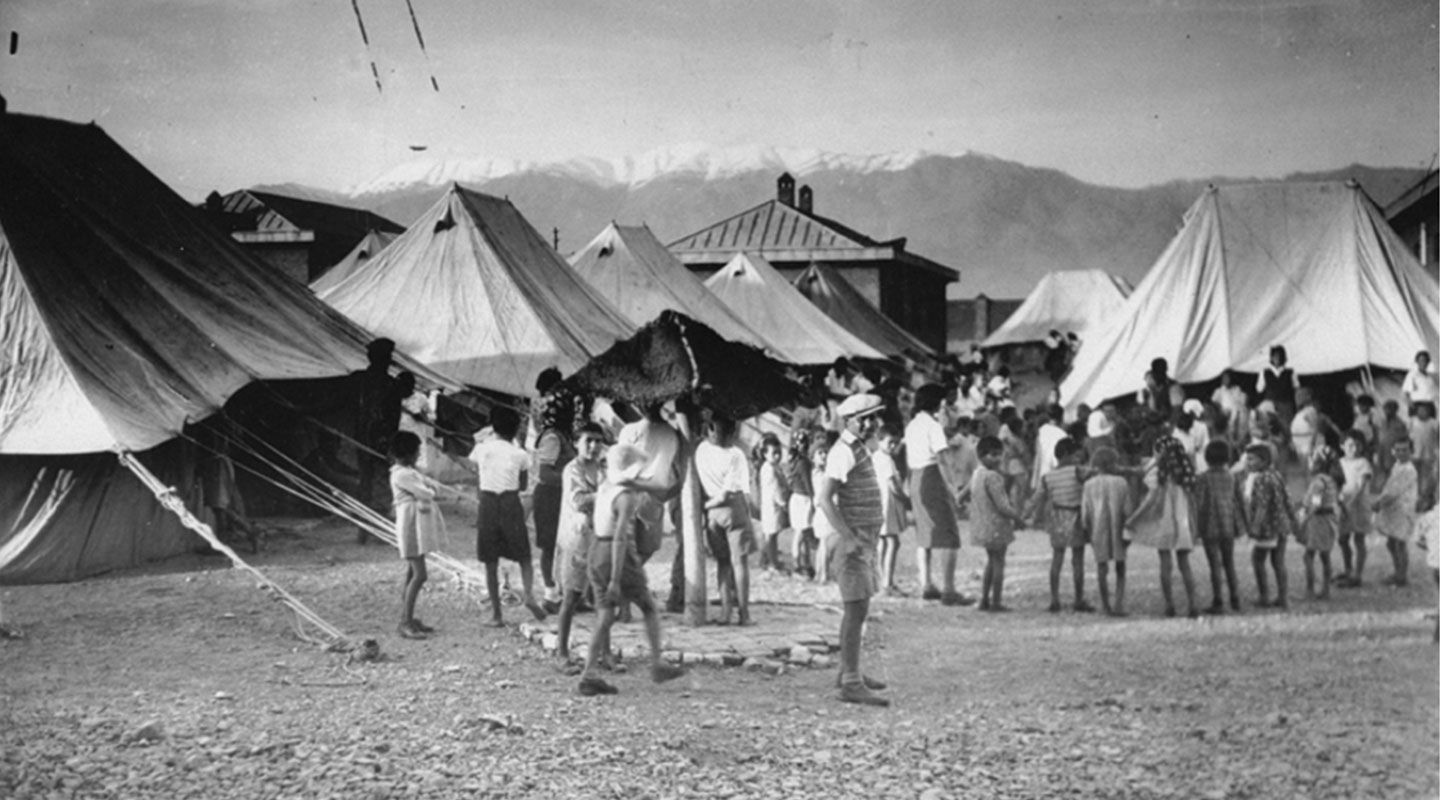 A black and white picture of a group of children in front of tents in Iran.