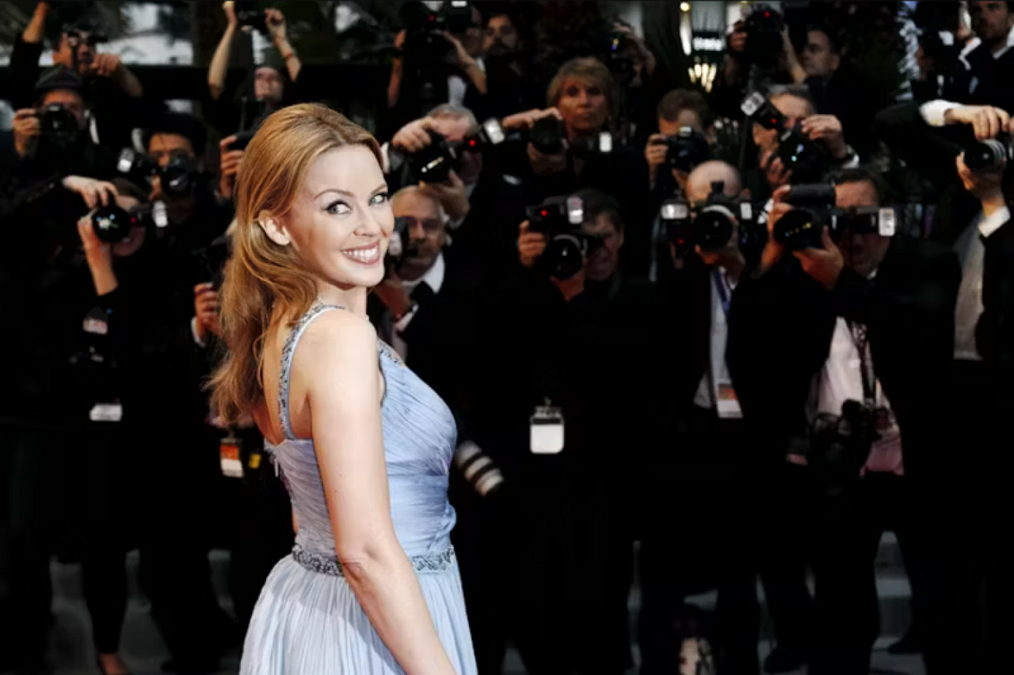 Kylie Minogue standing in front of photographers at a celebrity event.