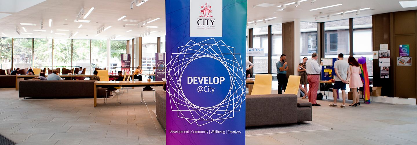 Develop at City roller banner with staff in the background in the pavilion