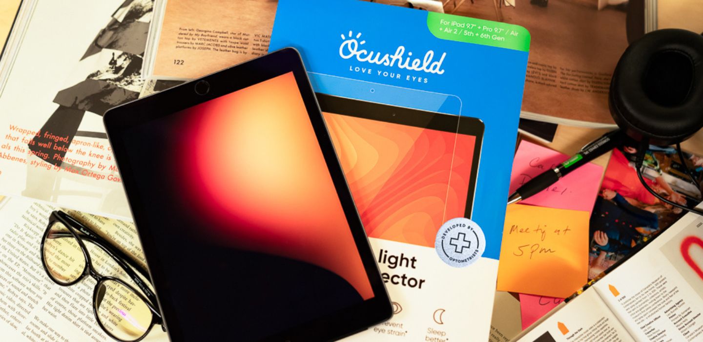 Tablet beside Ocushield ipad screen protector packaging on top of magazines