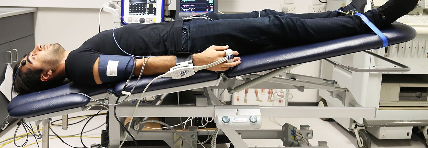 Patient lays on a tilted table with wires attached that are linked to a computer.
