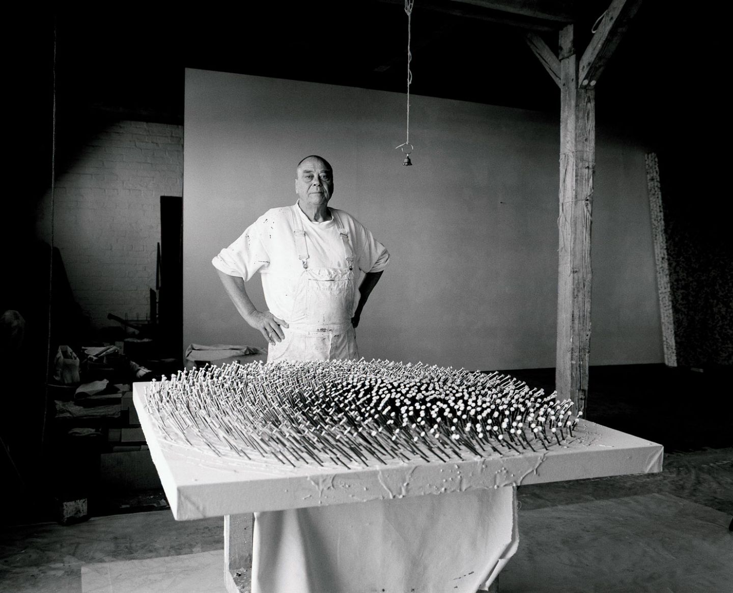 Artist Günther Uecker standing in front of his artwork, a bed of nails