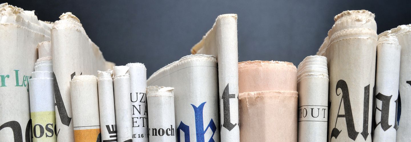 An image of a row of newspapers folded. We can only see the folded spine of paper.