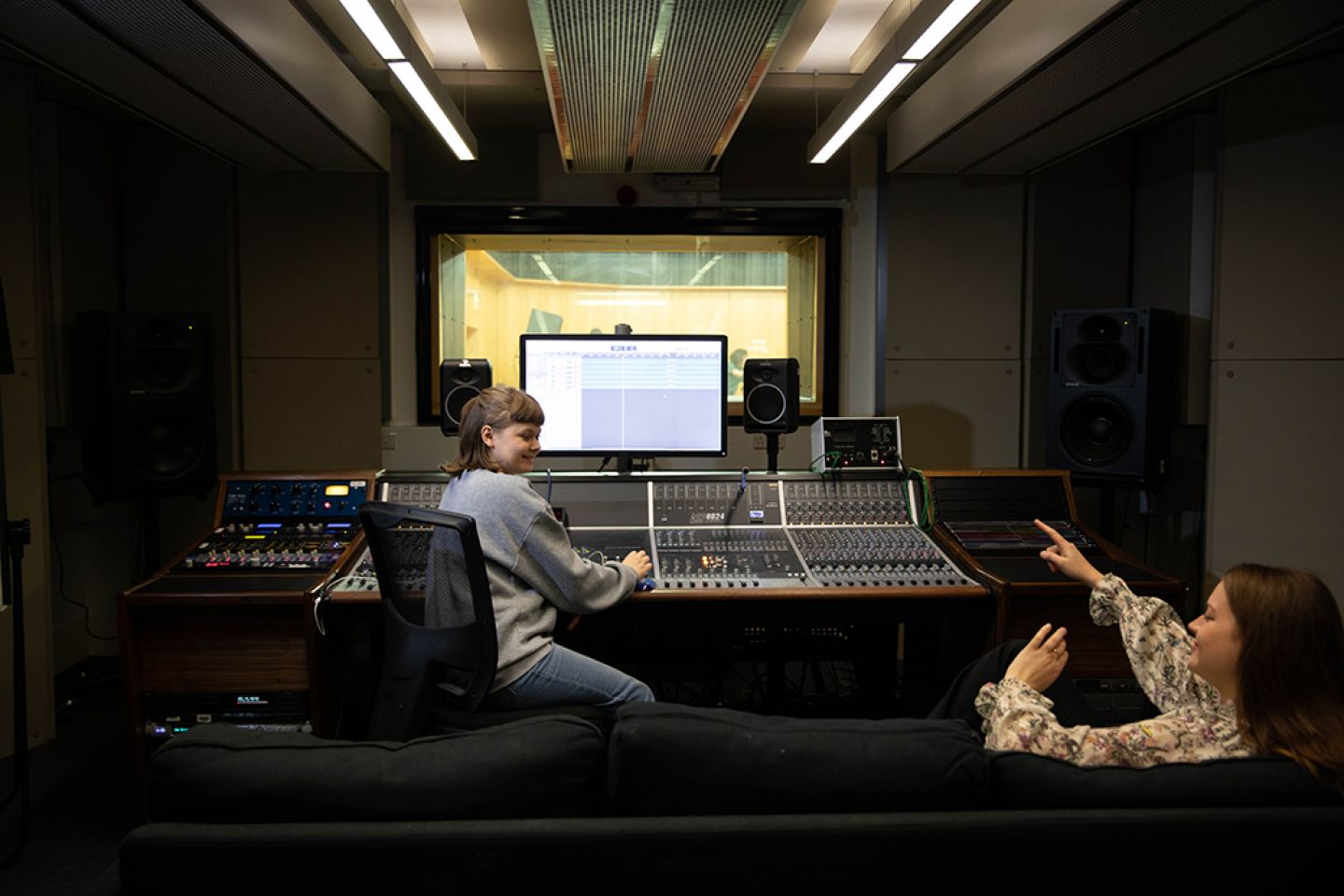 Two female undergraduate students using music studios onlooking the performance space