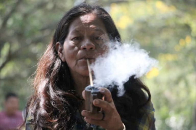 Indigenous Brazilian person smoking a pipe