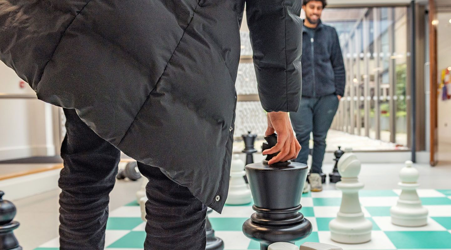 Students playing oversize chess on the floor.