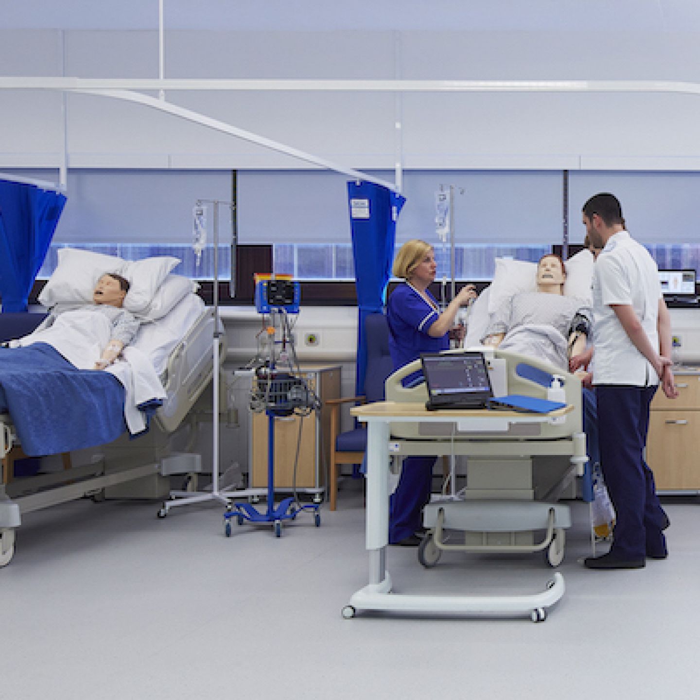 Nurses standing next to patients in beds in the clinical suite