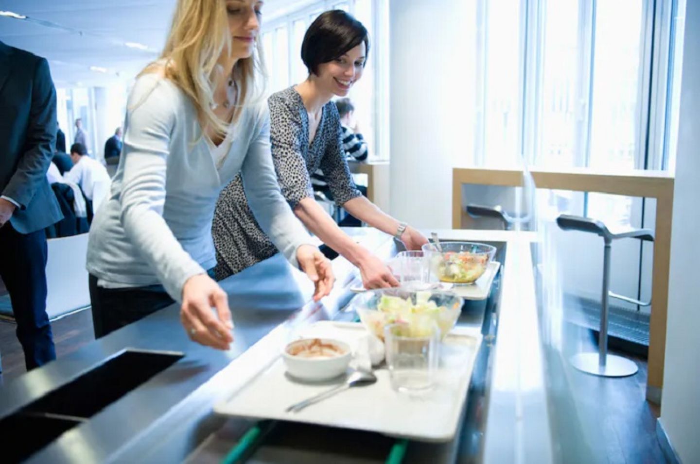 Two women standing with food trays on a counter