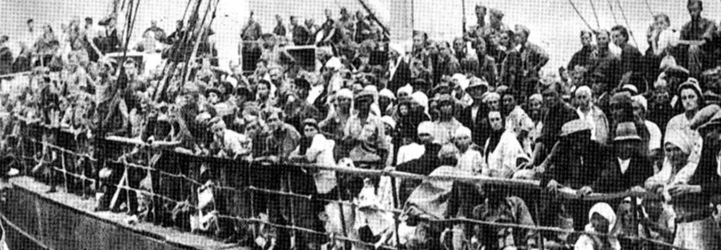 A black and white picture with many people standing on boat. 