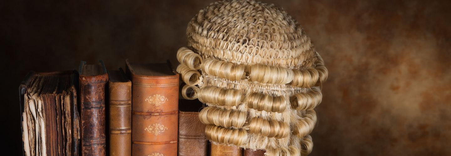 Antique judge's wig hanging on some very old books