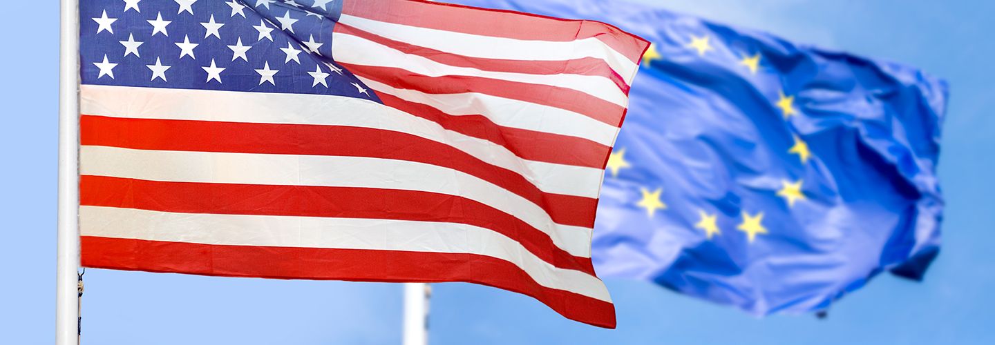 American and European union flags over a blue sky