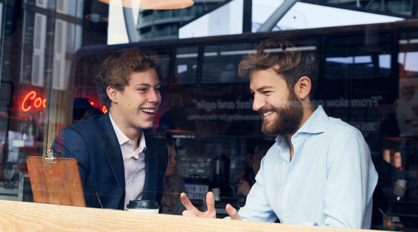 Two male students having a chat inside a coffee shop.