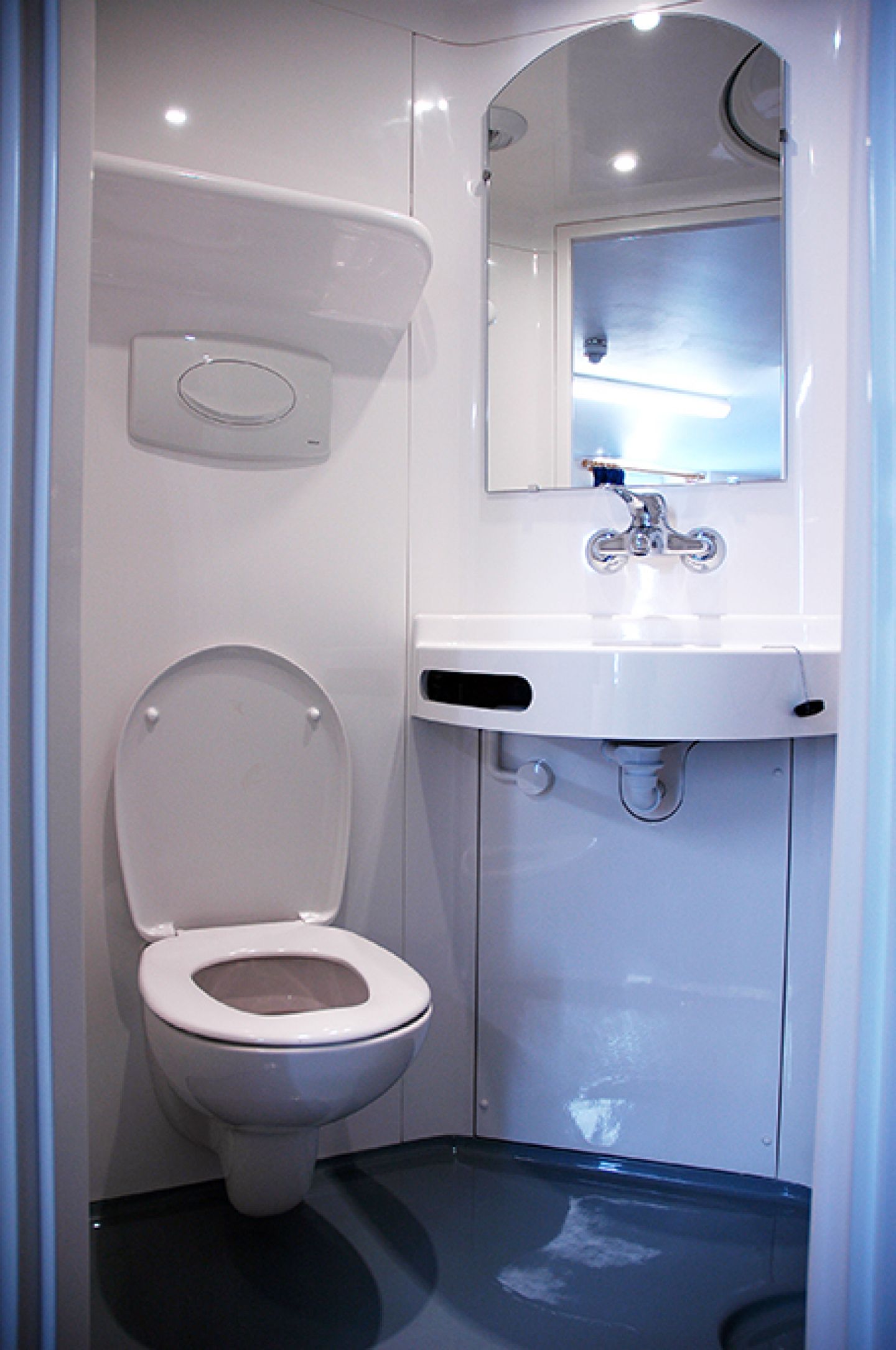 Interior of the en-suite bathroom showing the built-in toilet and sink with a mirror above it, all in clean white.