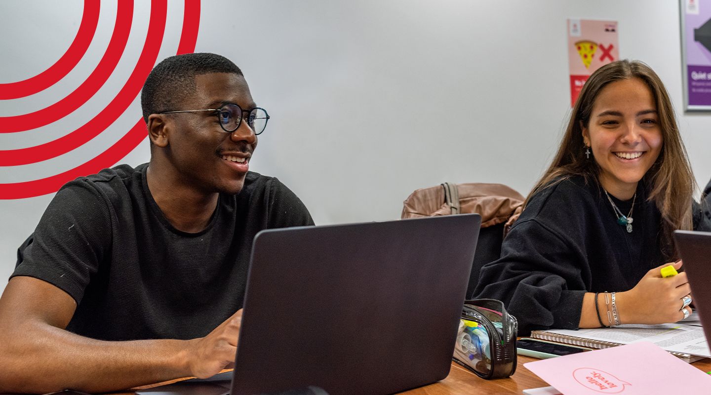 Man and Female student smiling working on laptops smiling