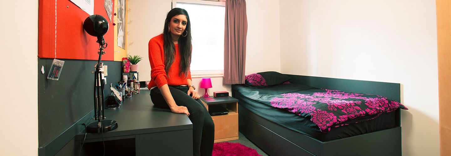 Female student sitting on desk in bedroom